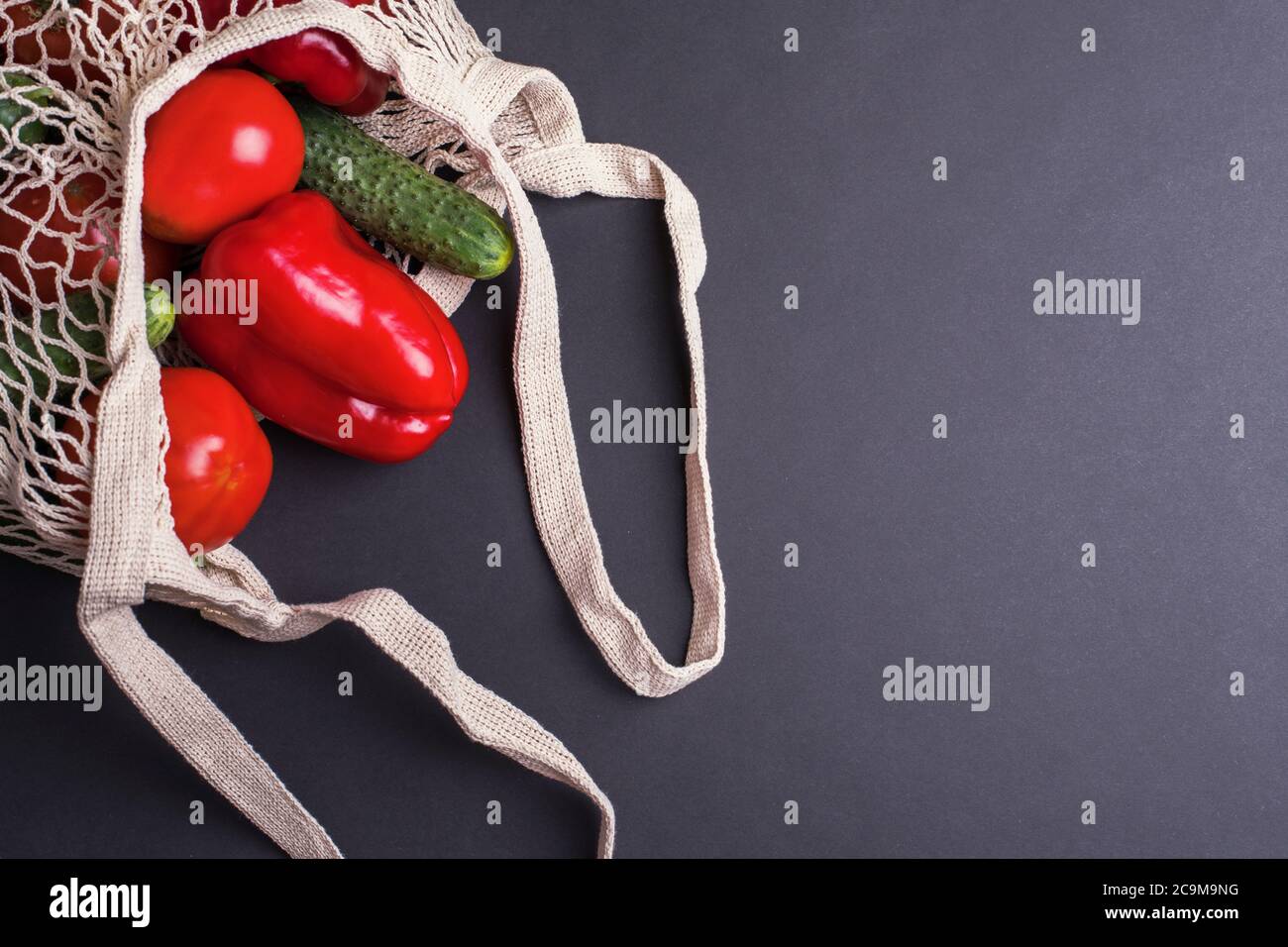 Borsa eco a filo con cetrioli di verdure e pomodori su sfondo nero. Zero ovest Foto Stock