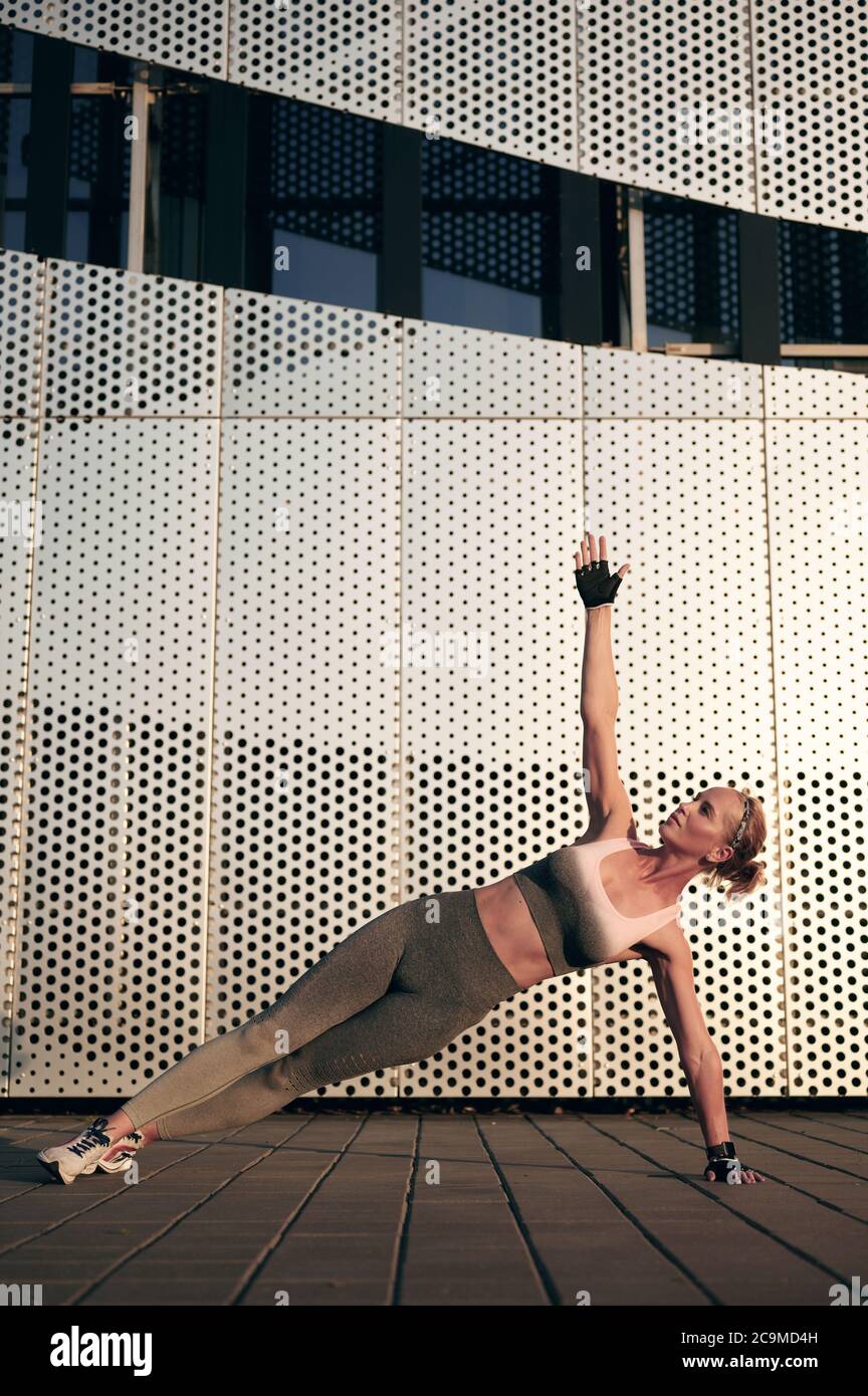 Fit donna forte in piedi in posizione laterale Plank, Vasissthasana mentre si pratica yoga all'aperto, in città. Stile di vita sano e concetto di relax Foto Stock