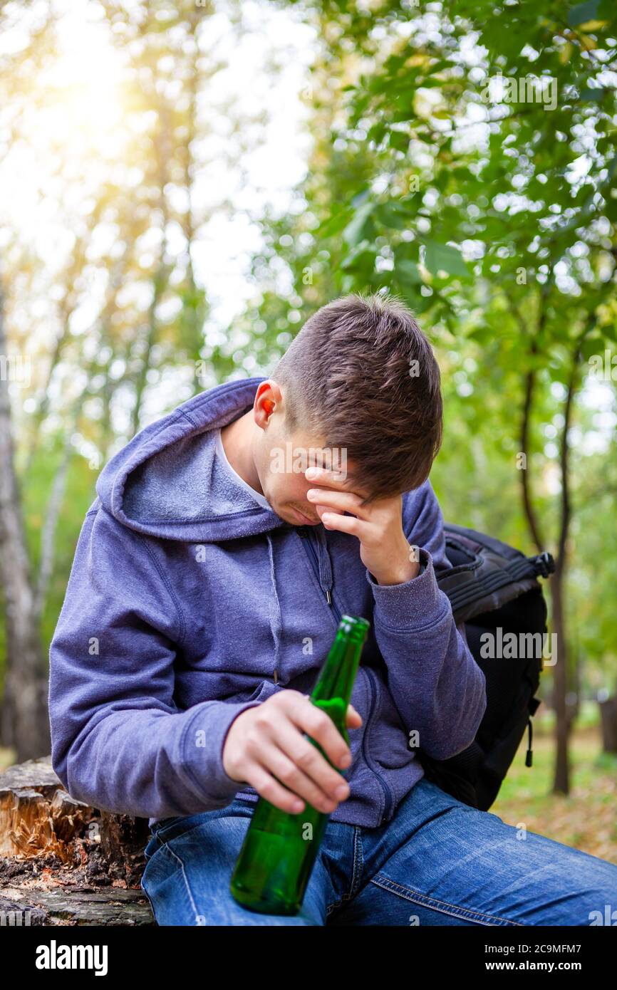 Sad Young Man con una bottiglia di birra nel Parco Foto Stock