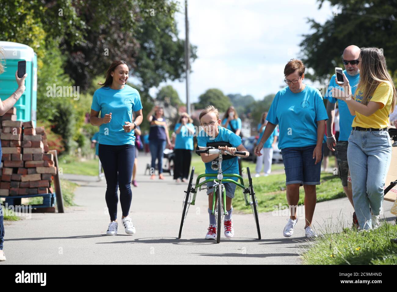 Tobias Weller, che ha paralisi cerebrale e autismo, accanto all'atleta olimpico Jessica Ennis-Hill (a sinistra), ha quasi completato la sua nuova sfida di correre una maratona in strada fuori casa a Sheffield, utilizzando un corridore di gara. Tobias, che non può stare in piedi o camminare senza aiuto, è stato ispirato dal Capitano Tom Moore a completare la sua prima maratona nelle sue passeggiate giornaliere di ritorno in aprile. Foto Stock