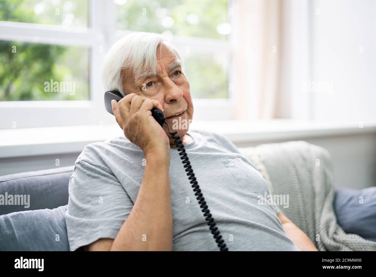 Anziano anziano che parla sul telefono fisso Foto Stock