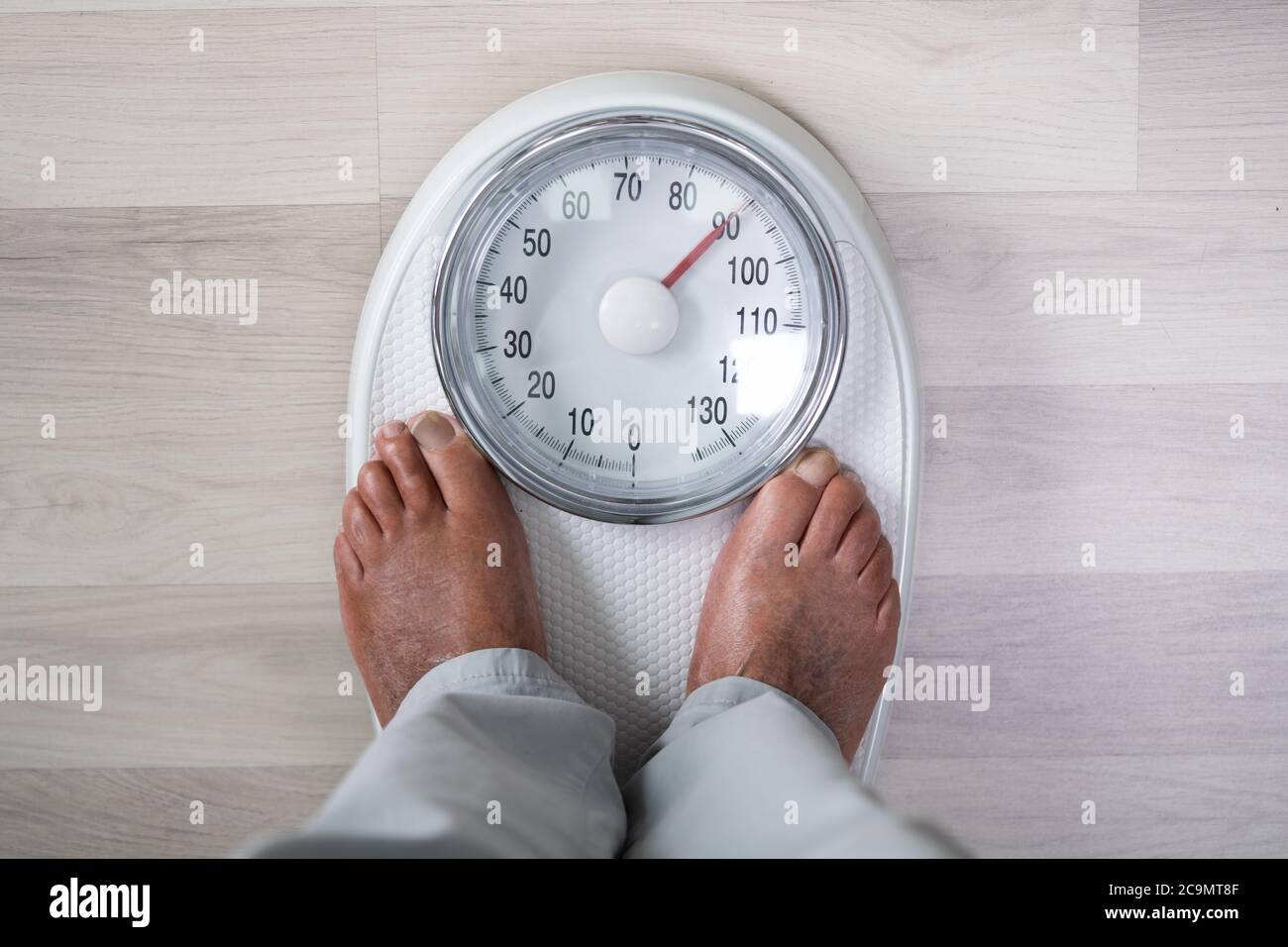 Man piedi su scala di peso. Obesità e colesterolo alto Foto Stock