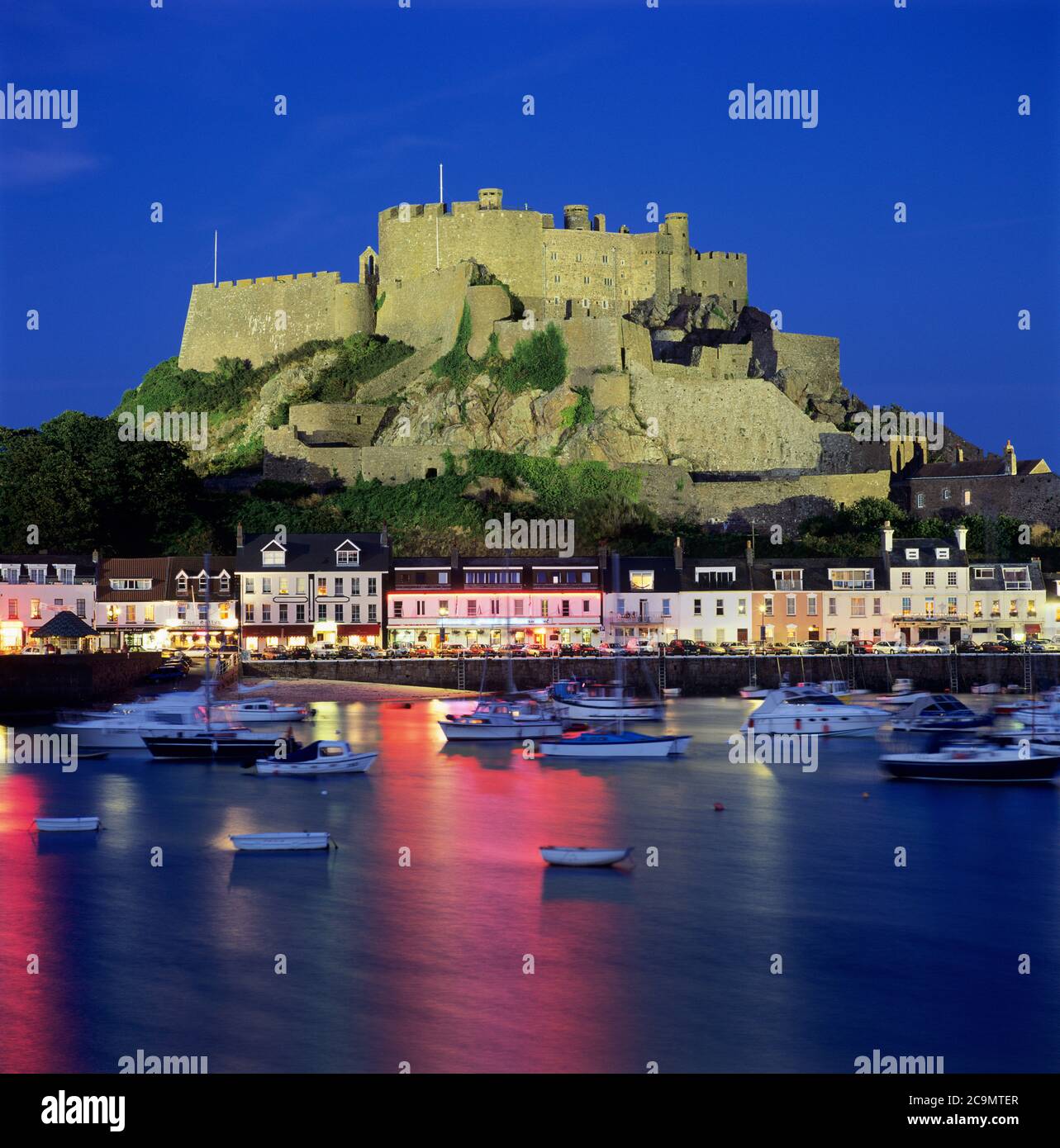 Mont Orgueil Castello che domina il porto e illuminato di notte, Gorey, Jersey, Regno Unito Foto Stock