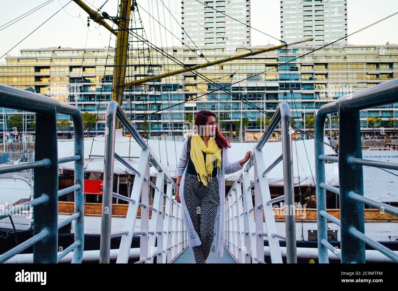 Una donna brasiliana rossa nei suoi anni 20 entrando in una grande barca parcheggiata nella zona degli affari di Puerto Madero e guardando al lato e sorridendo. Foto Stock