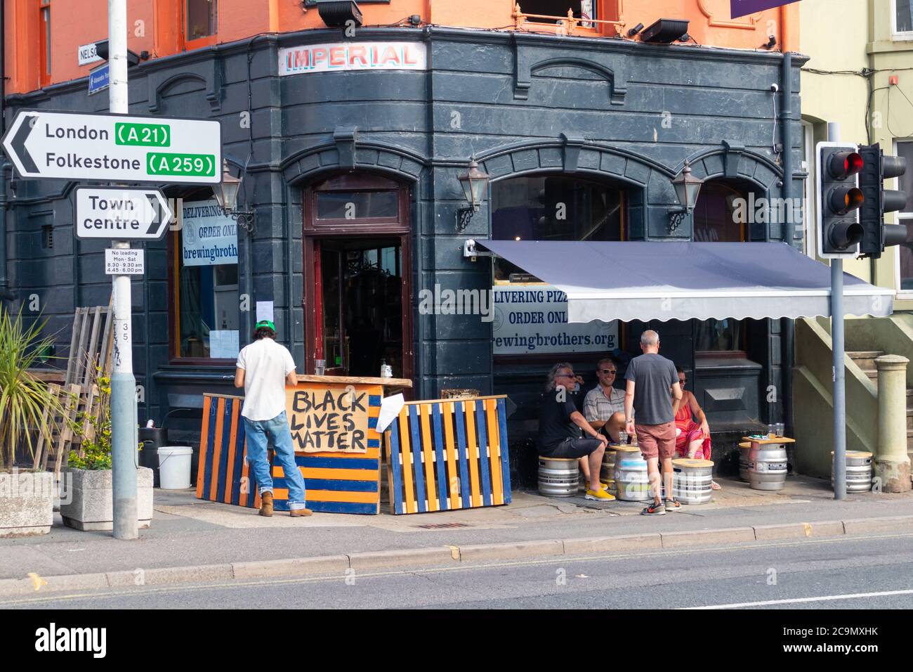 Pub che serve i clienti all'esterno con il segno nero della materia della vita su bar, hastings, sussex orientale, regno unito Foto Stock