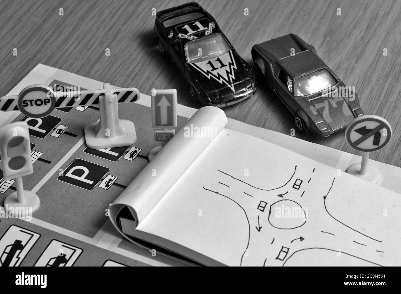 Blocco note, libro delle regole del traffico, Toy Cars, semafori e segno di stop su una scrivania. Studiare e prepararsi per il test di guida Foto Stock