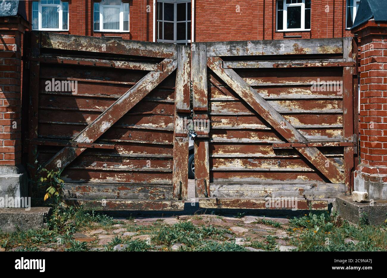 Cancelli di legno di shabby con una serratura vicino casa di campagna di mattoni Foto Stock