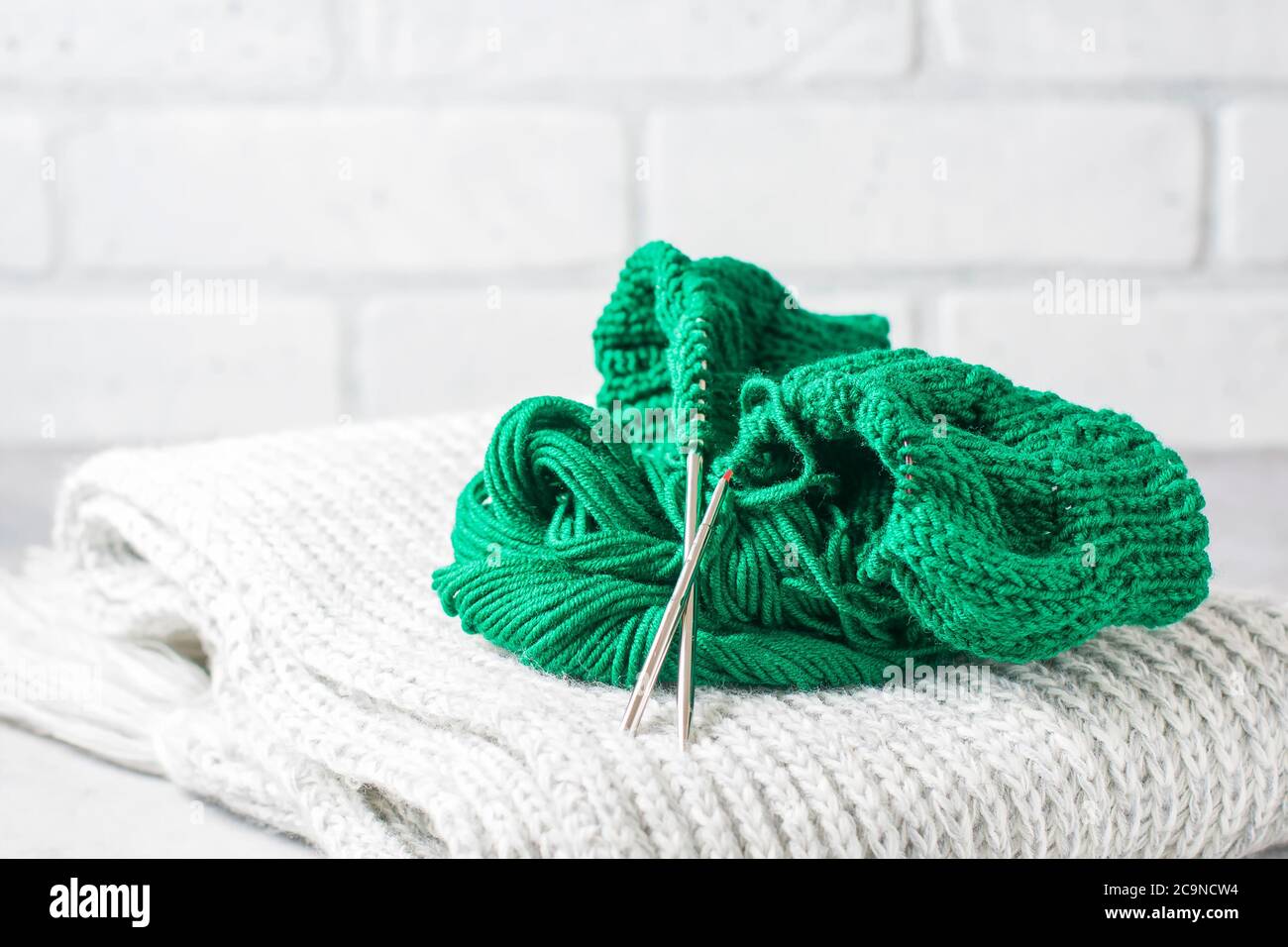 Filo verde per maglieria e aghi da maglieria da vicino. Messa a fuoco selettiva Foto Stock