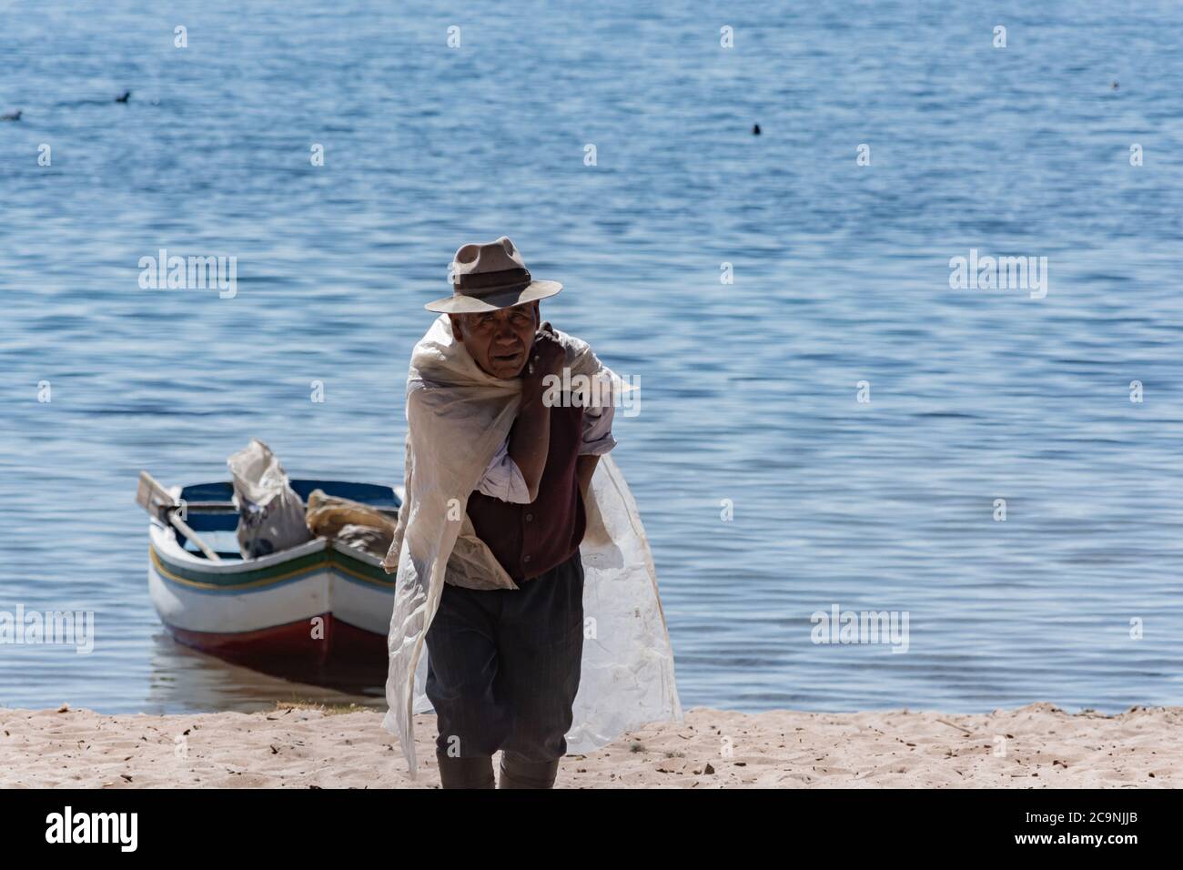 ISLA DEL Sol, BOLIVIA - 26 LUGLIO 2016: Un uomo boliviano anziano non identificato trasporta un sacchetto di cemento nel lato nord dell'Isla del Sol, Bolivia Foto Stock