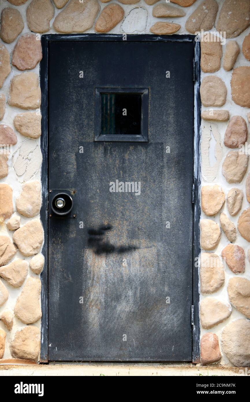Una porta nera che guarda misteriosa circondata da un muro di pietra. Foto Stock