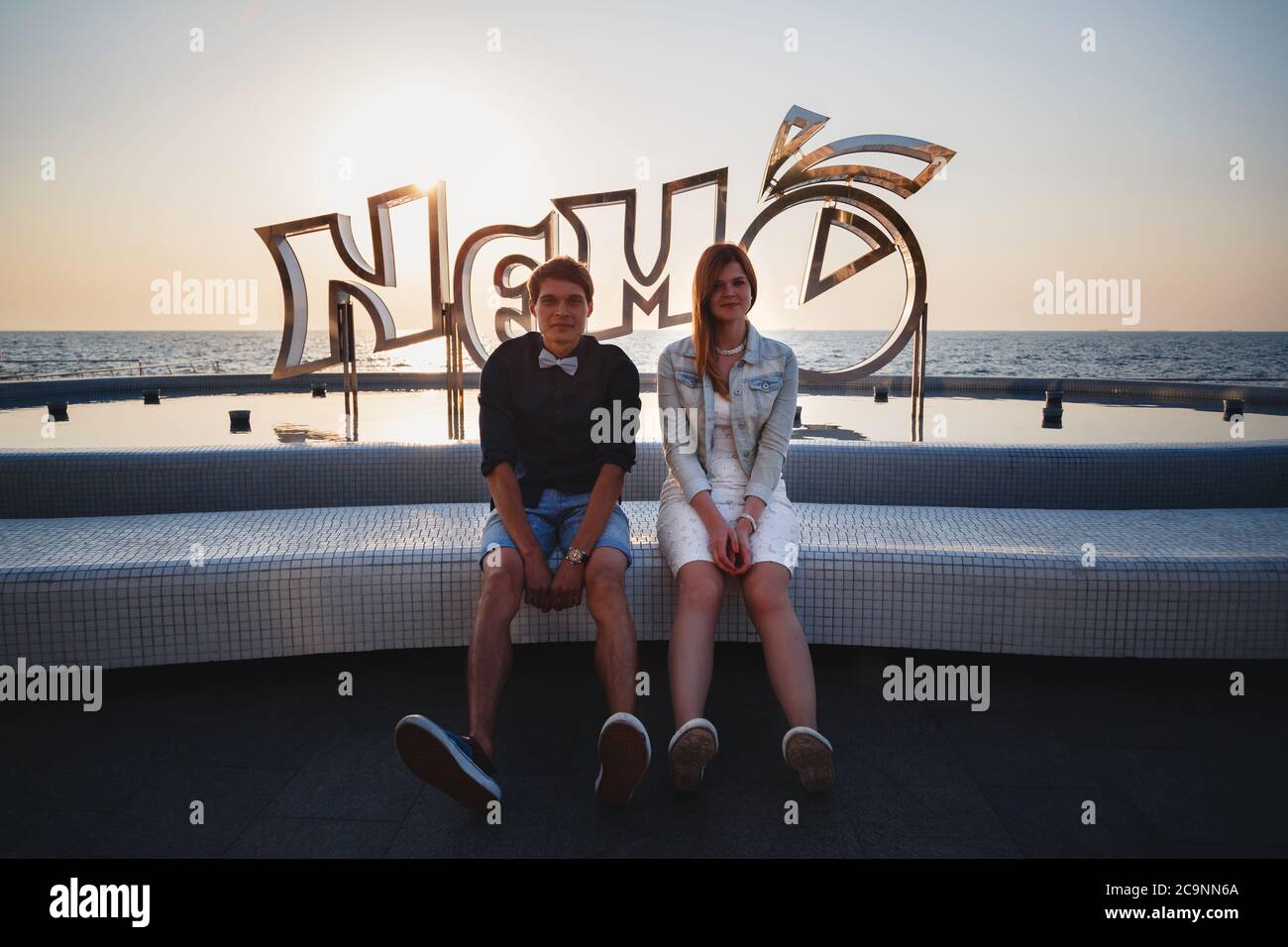 ODESSA, UCRAINA - 06 AGOSTO 2015: Primo piano di felice giovane coppia seduta vicino alla piscina di Nemo delfinarium, concetto di viaggio Foto Stock