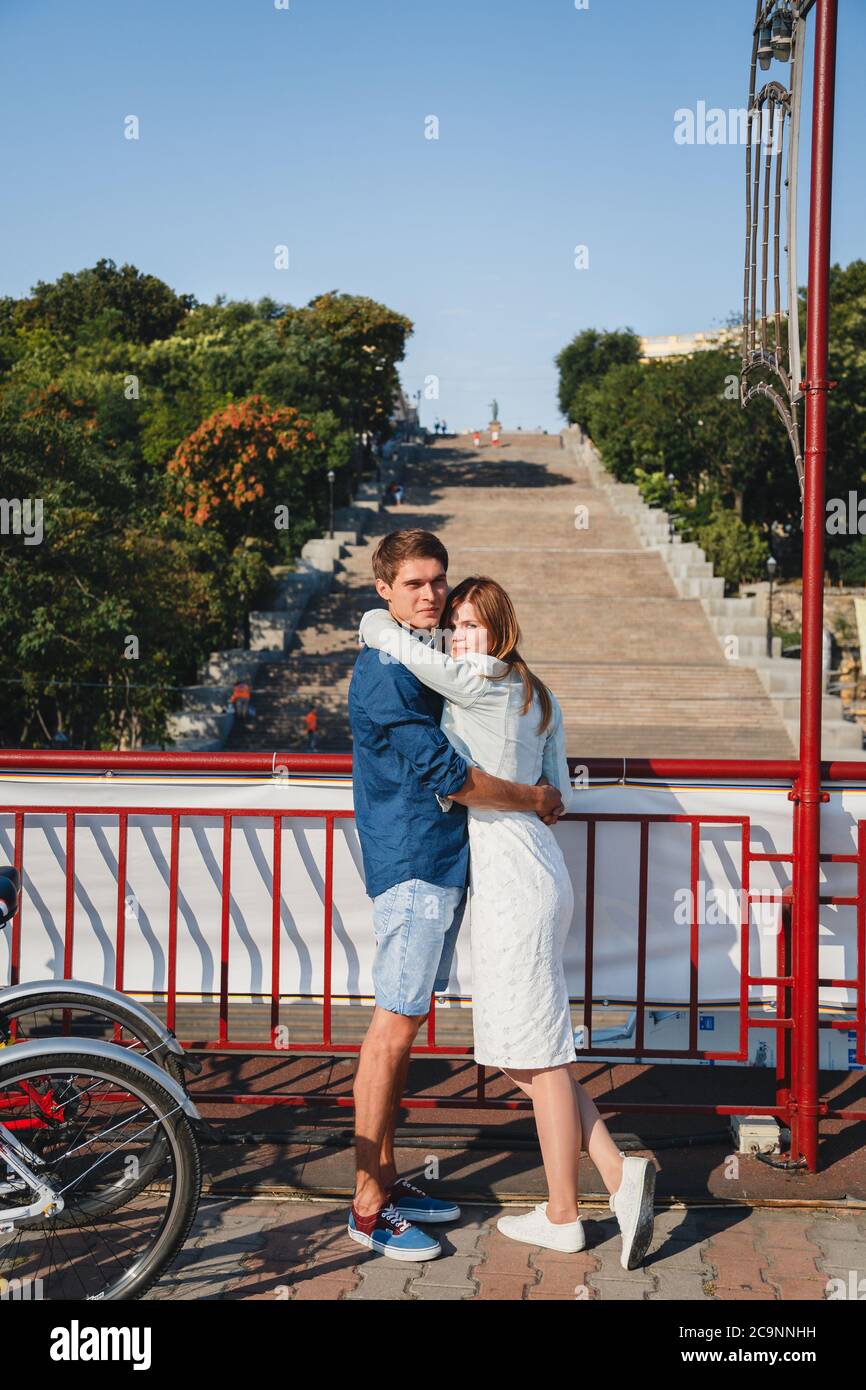 ODESSA, UCRAINA - 06 AGOSTO 2015: Carino giovane bella coppia hipster abbracciando con Potemkin Scale sullo sfondo, felice sorridente ritratto all'aperto Foto Stock