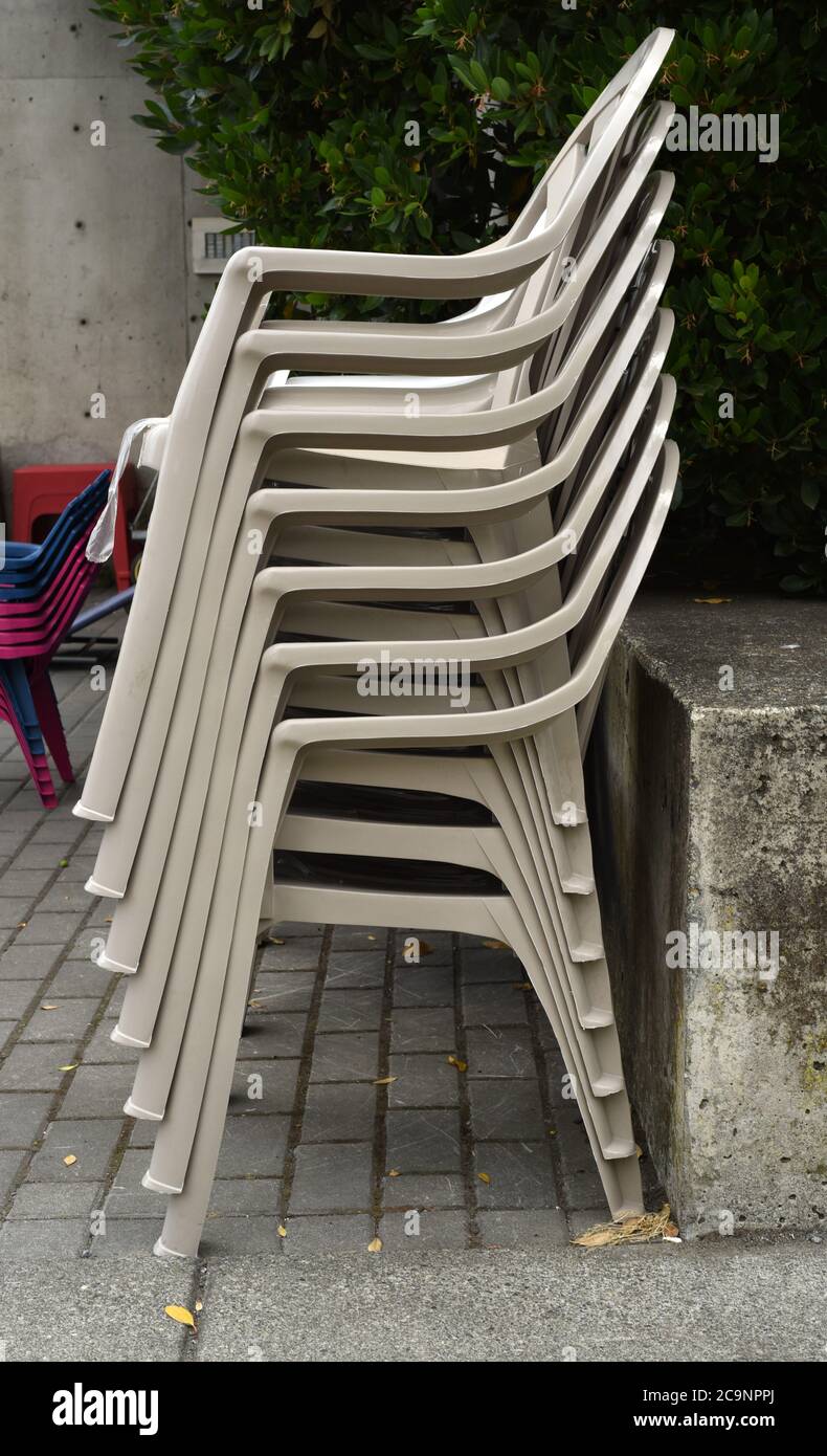 Una pila di sedie impilabili o annidabili in plastica per la vendita al di fuori di un negozio di ferramenta Foto Stock