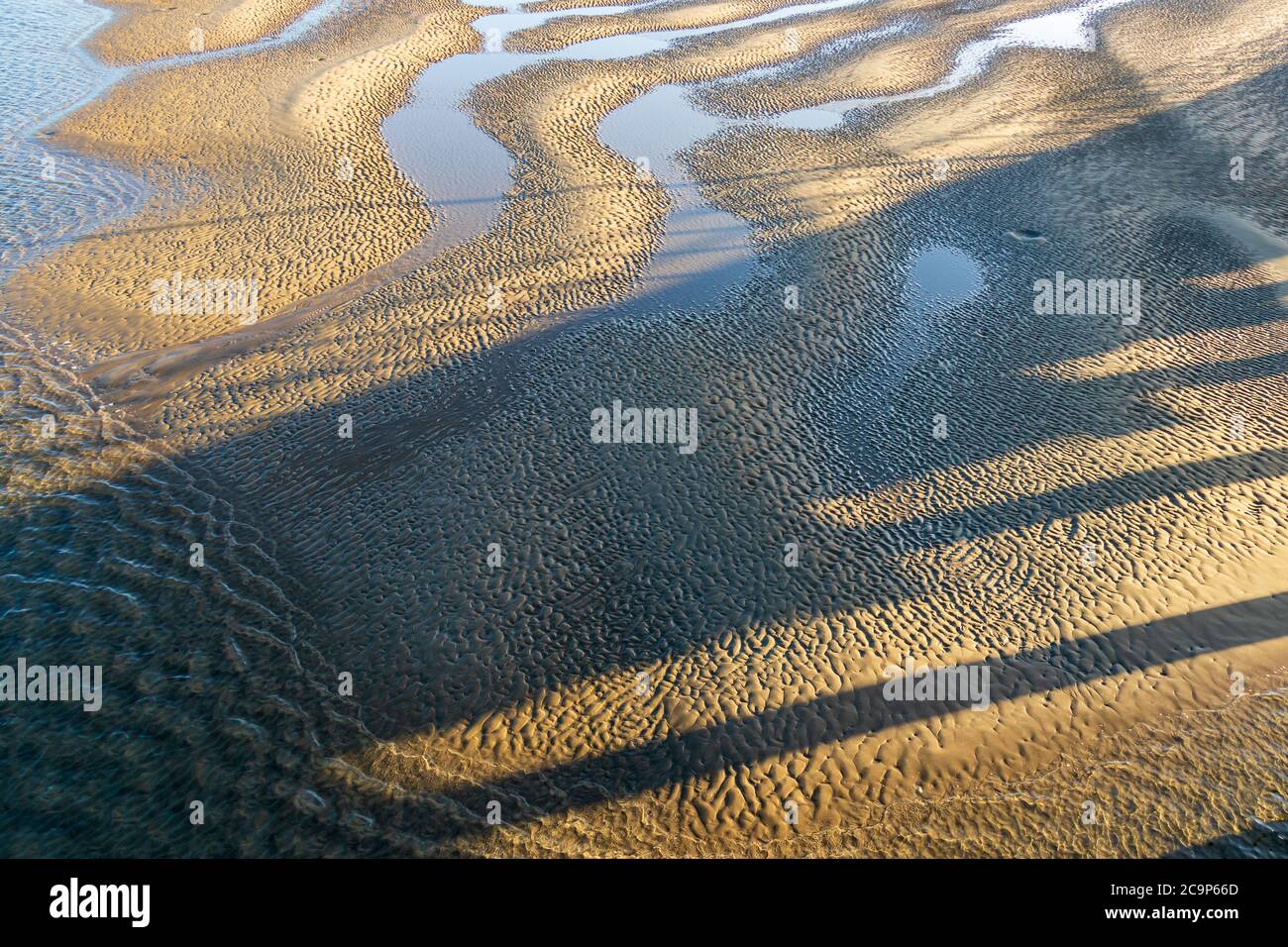 Modelli di sabbia a bassa marea e ombre Foto Stock