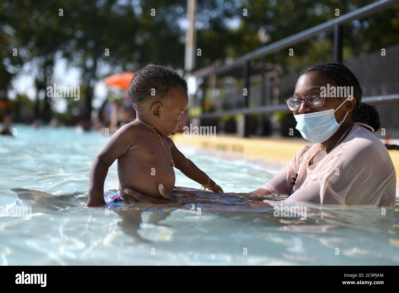 New York City, Stati Uniti. 01 agosto 2020. Jazmine Carr detiene il suo figlio di nove mesi mentre si trova nella parte bassa della piscina all'aperto dell'Astoria Park il giorno di apertura, che era stata chiusa a causa della pandemia COVID-19, nel quartiere Queens di New York, NY, 1 agosto 2020. Il New York City Parks Department ha aperto oggi altre sette piscine pubbliche sotto la fase IV riapertura, con un totale di quindici in tutti e cinque i distretti, dove le maschere sono necessarie a meno che nella piscina stessa, e osservando la distanza sociale come meglio possibile. (Anthony Behar/Sipa USA) Credit: Sipa USA/Alamy Live News Foto Stock