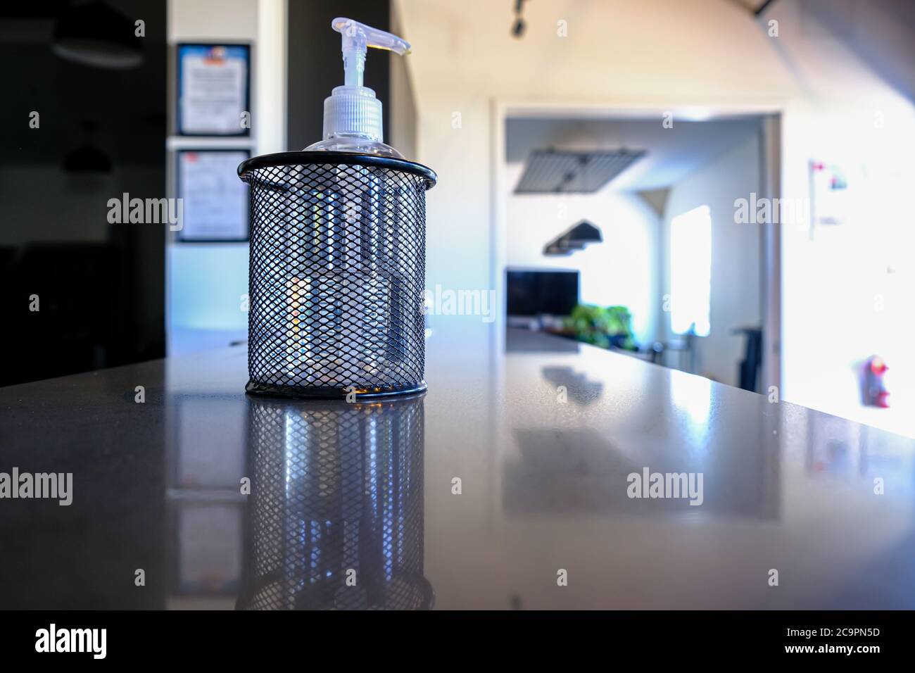 Bottiglia di disinfettante per mani al banco della reception dell'ufficio per aiutare a pulire le mani durante la pandemia di covid 19 Foto Stock