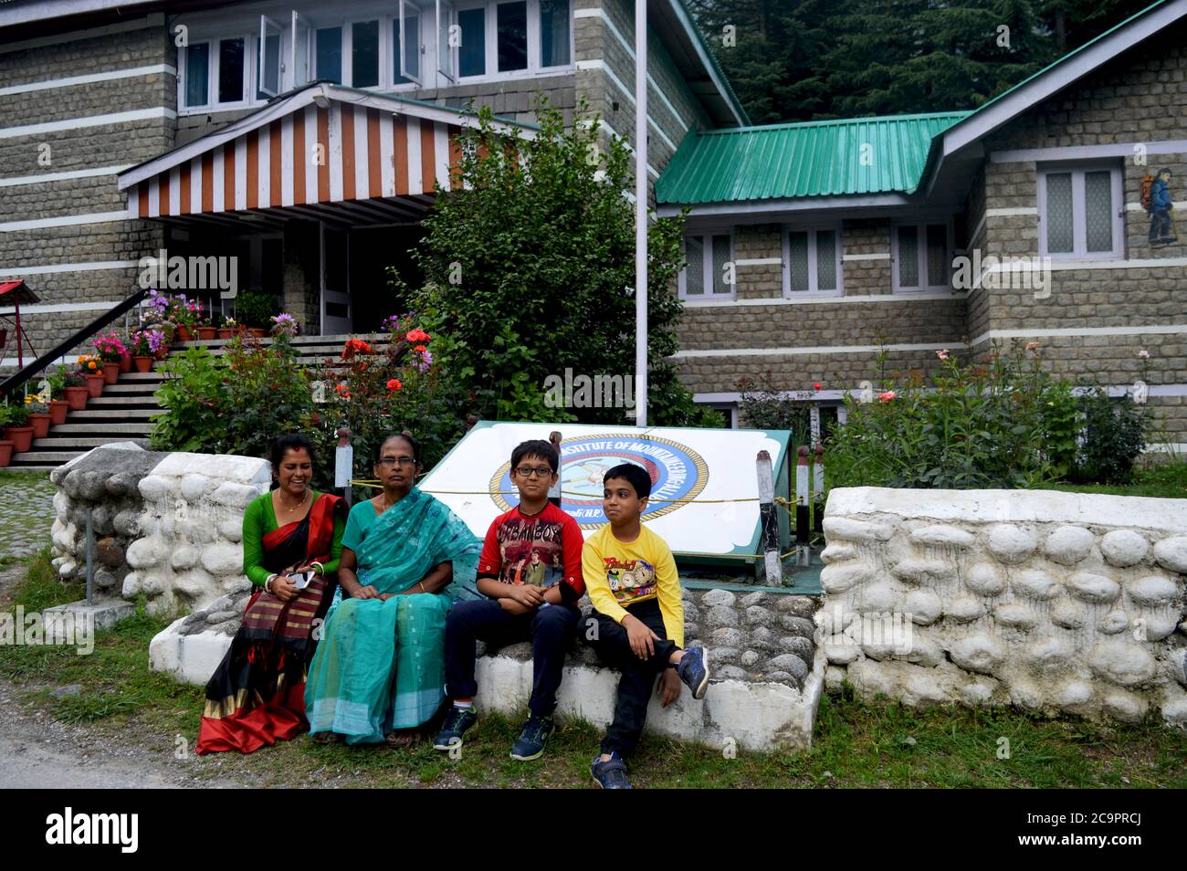 Due donne e bambini indiani seduti di fronte all'istituto di alpinismo AVBIMAS, Manali, focalizzazione selettiva Foto Stock