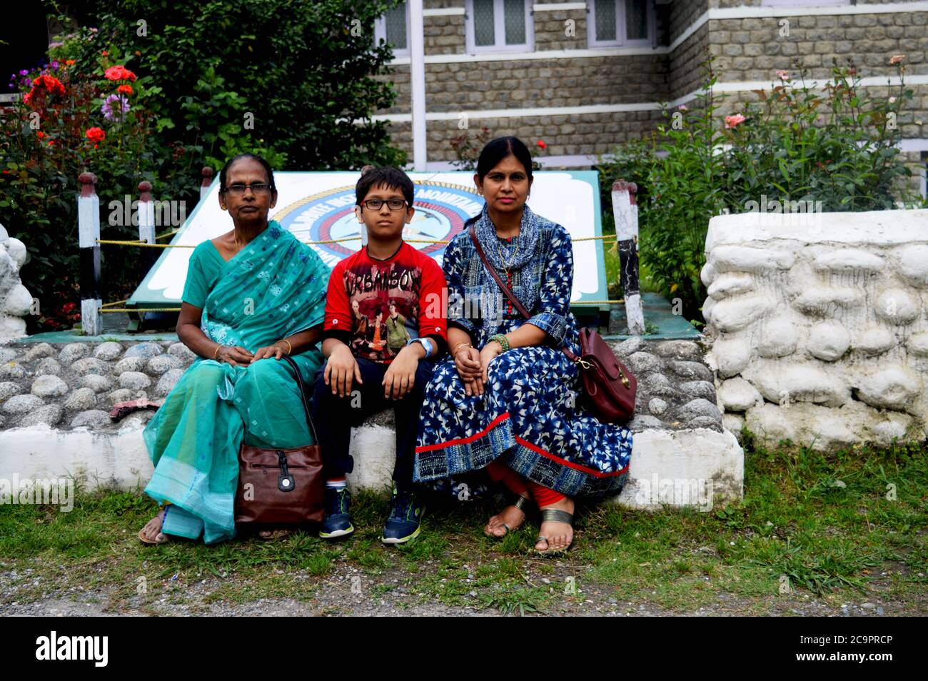 Due donne e bambini indiani seduti di fronte all'istituto di alpinismo AVBIMAS, Manali, focalizzazione selettiva Foto Stock