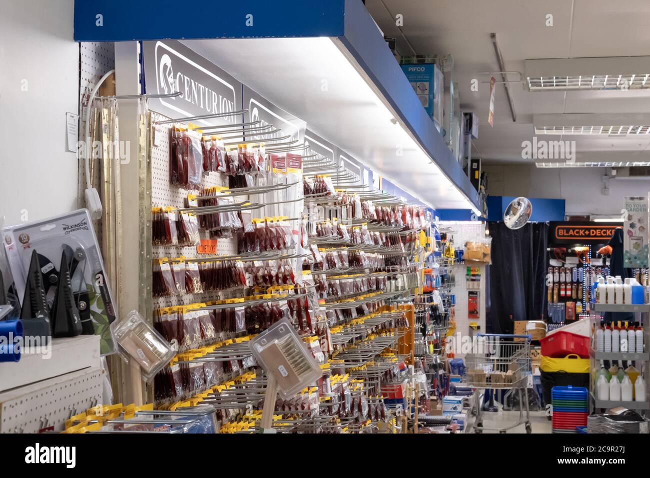 Vista interna di un negozio di ferramenta generale e fai da te che mostra i vari componenti hardware e strumenti in esposizione. La sezione è ben illuminata da luci di tubo verso il basso Foto Stock