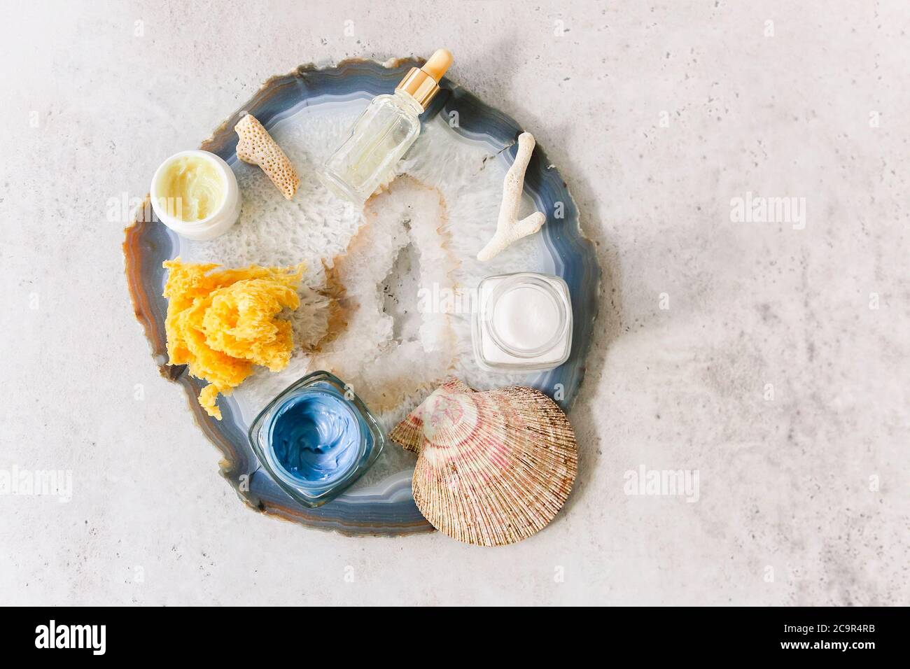 Vista dall'alto di vari prodotti cosmetici in vasi disposti su tavolo con conchiglie e pietra minerale Foto Stock