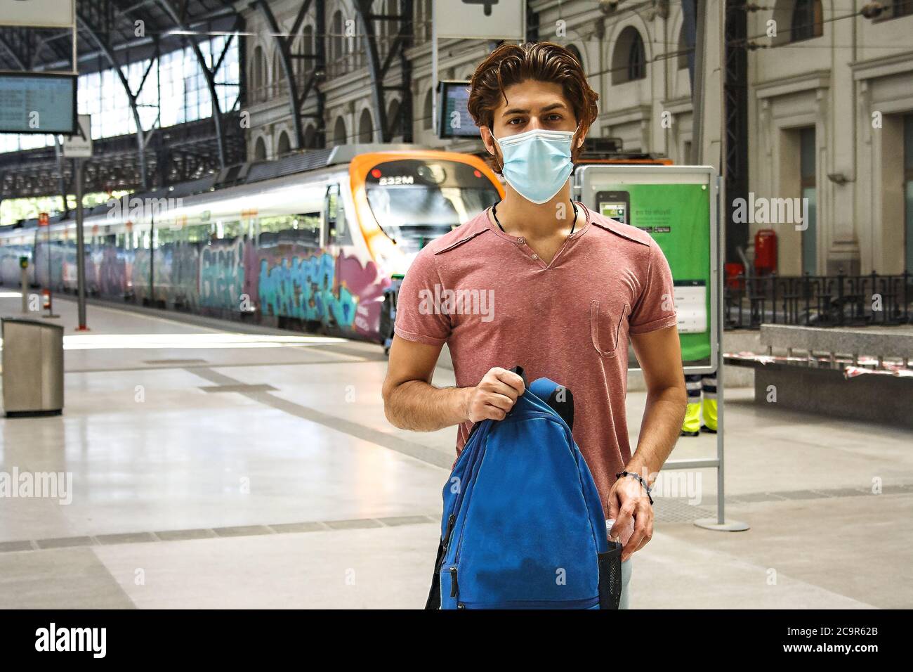 Giovane uomo che lascia la stazione ferroviaria con maschera facciale attivata. Aereo americano. Foto Stock