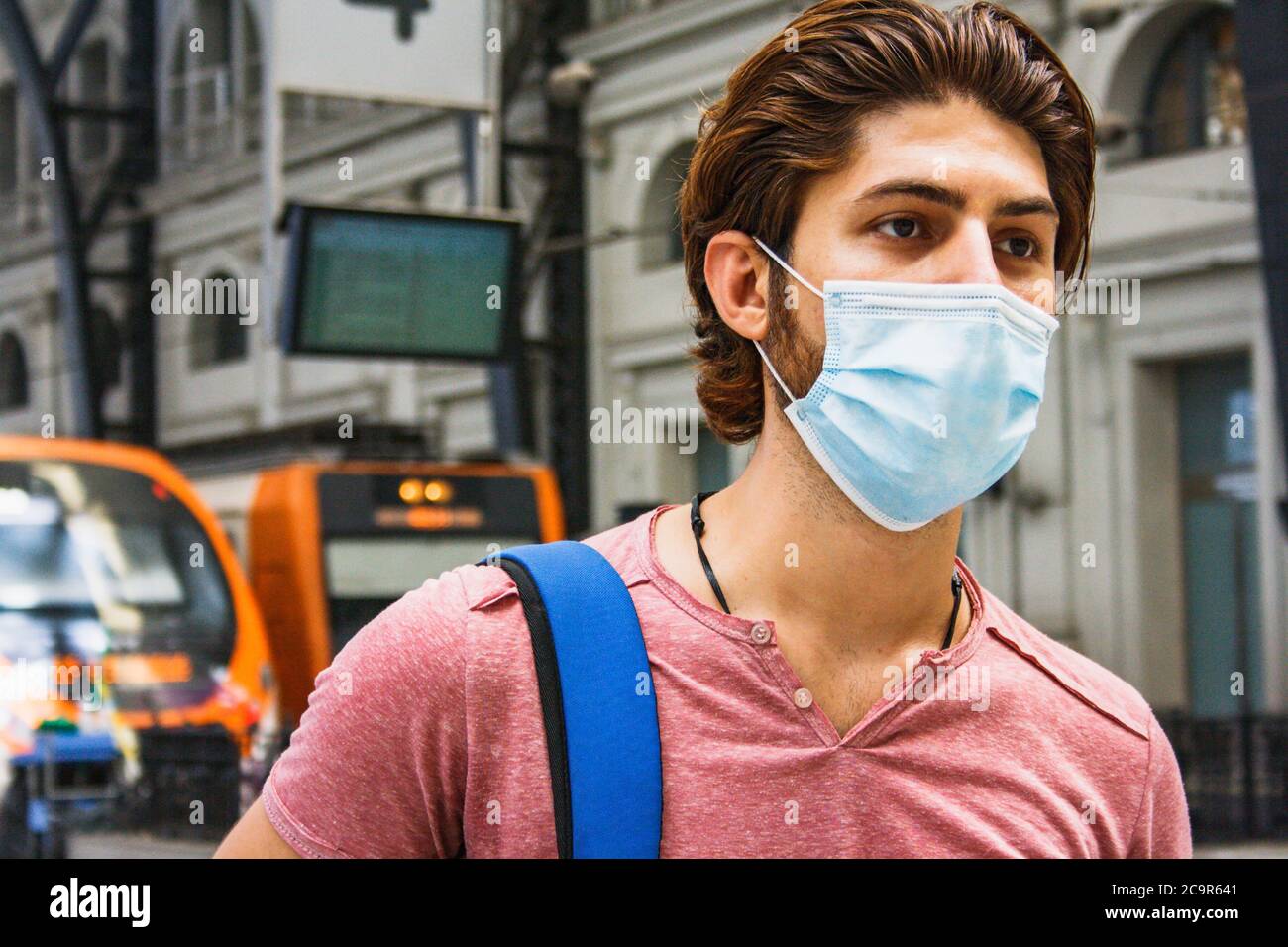 Giovane uomo che lascia la stazione ferroviaria con maschera facciale attivata. Primo piano. Foto Stock