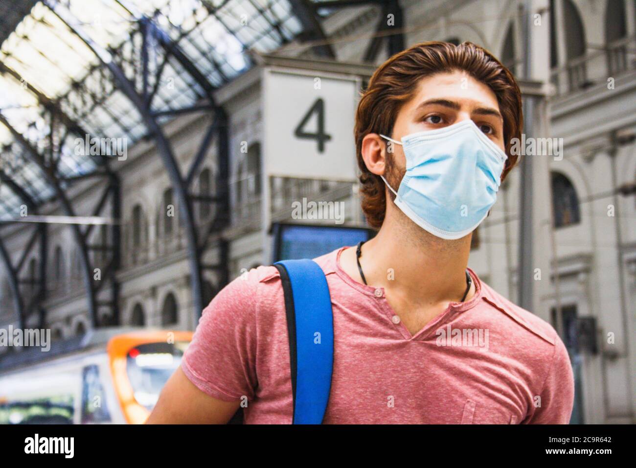 Giovane uomo che lascia la stazione ferroviaria con maschera facciale attivata. Primo piano. Foto Stock