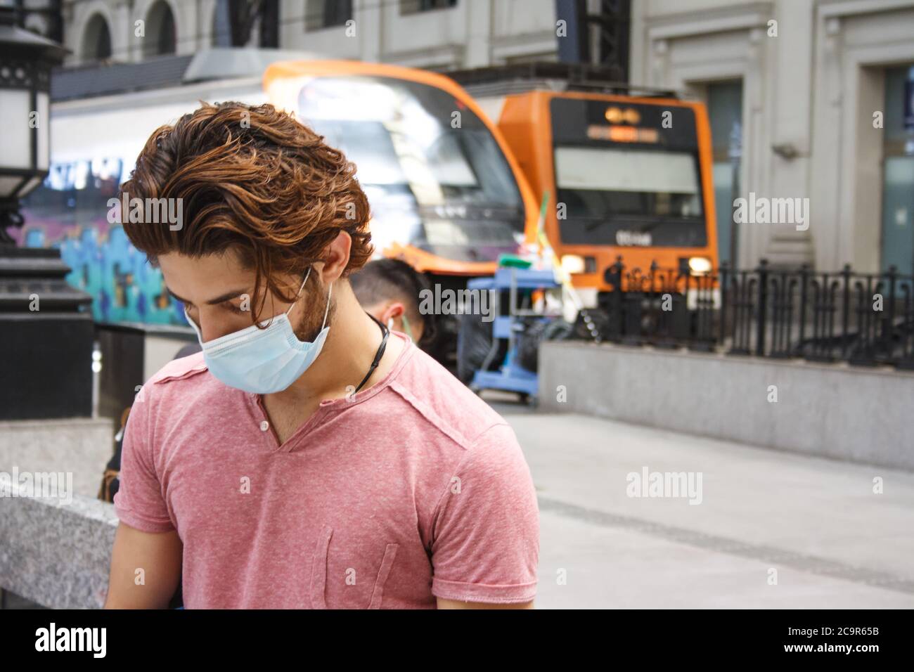 Giovane in attesa sulla stazione ferroviaria. Mantenere le misure di allontanamento sociale. Aereo medio corto sicuro. Foto Stock