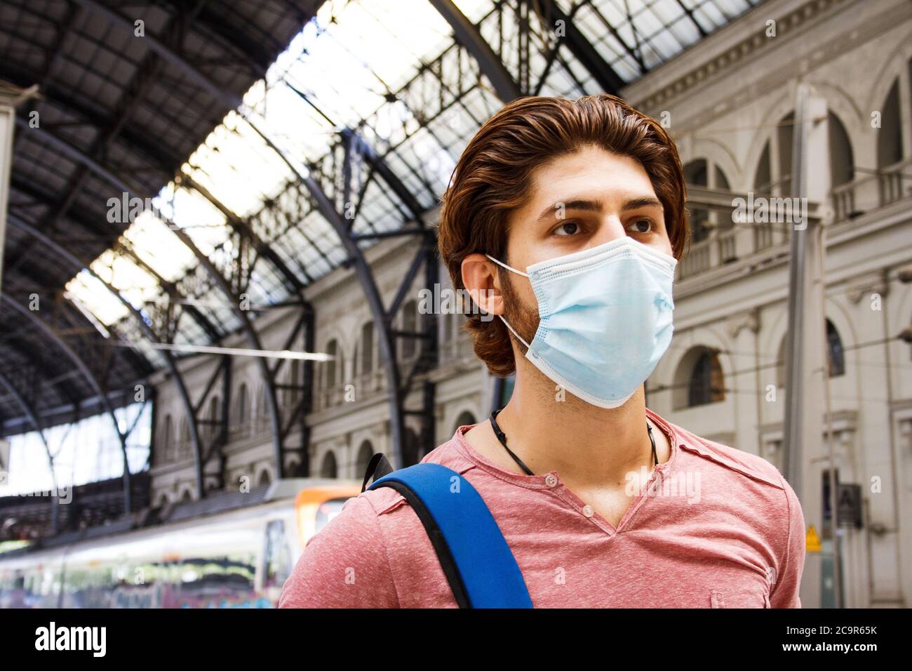 Giovane uomo che lascia la stazione ferroviaria con maschera facciale attivata. Primo piano. Foto Stock