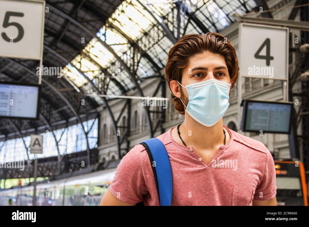 Giovane uomo che lascia la stazione ferroviaria con maschera facciale attivata. Primo piano. Foto Stock