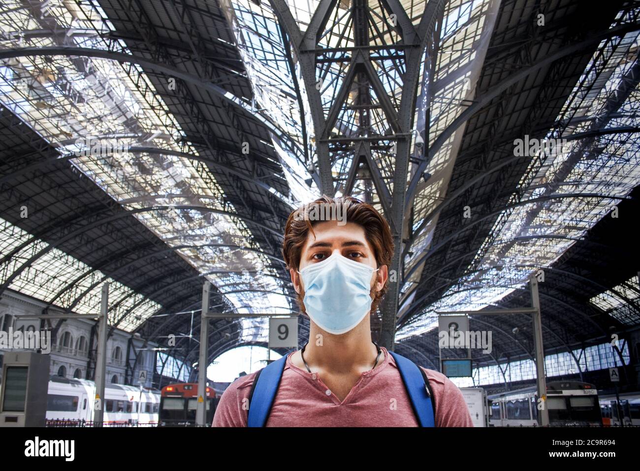 Giovane in stazione ferroviaria con maschera facciale attivata. Primo piano. Foto Stock