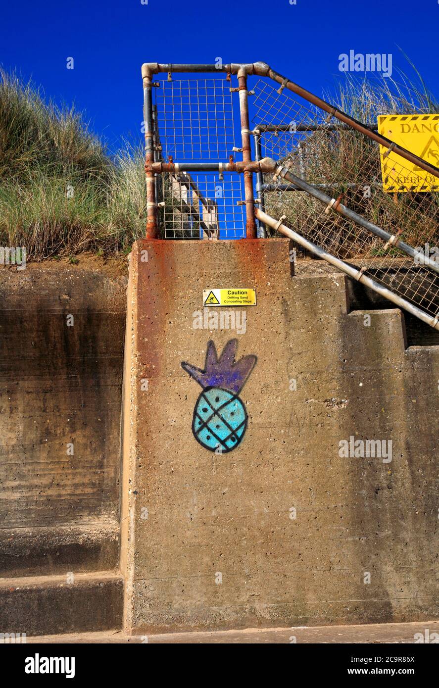 Le pareti del mare e l'accesso alla spiaggia attraverso dune di sabbia con graffiti sulla costa nord del Norfolk a Sea Palling, Norfolk, Inghilterra, Regno Unito. Foto Stock