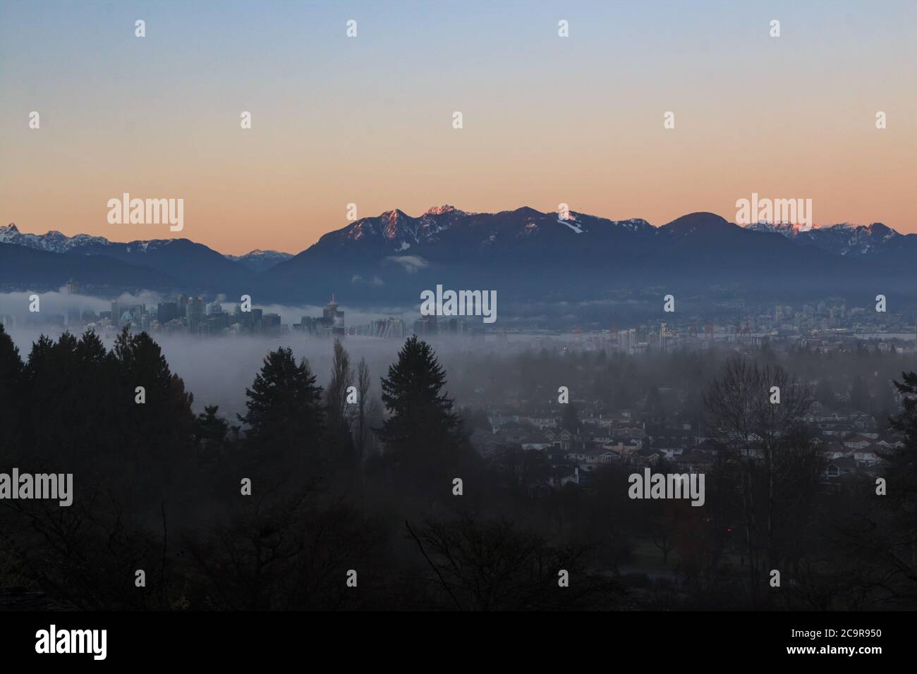 Skyline di Vancouver di notte - Vista aerea dal Queens Elizabeth Park in inverno con montagne innevate sullo sfondo Foto Stock