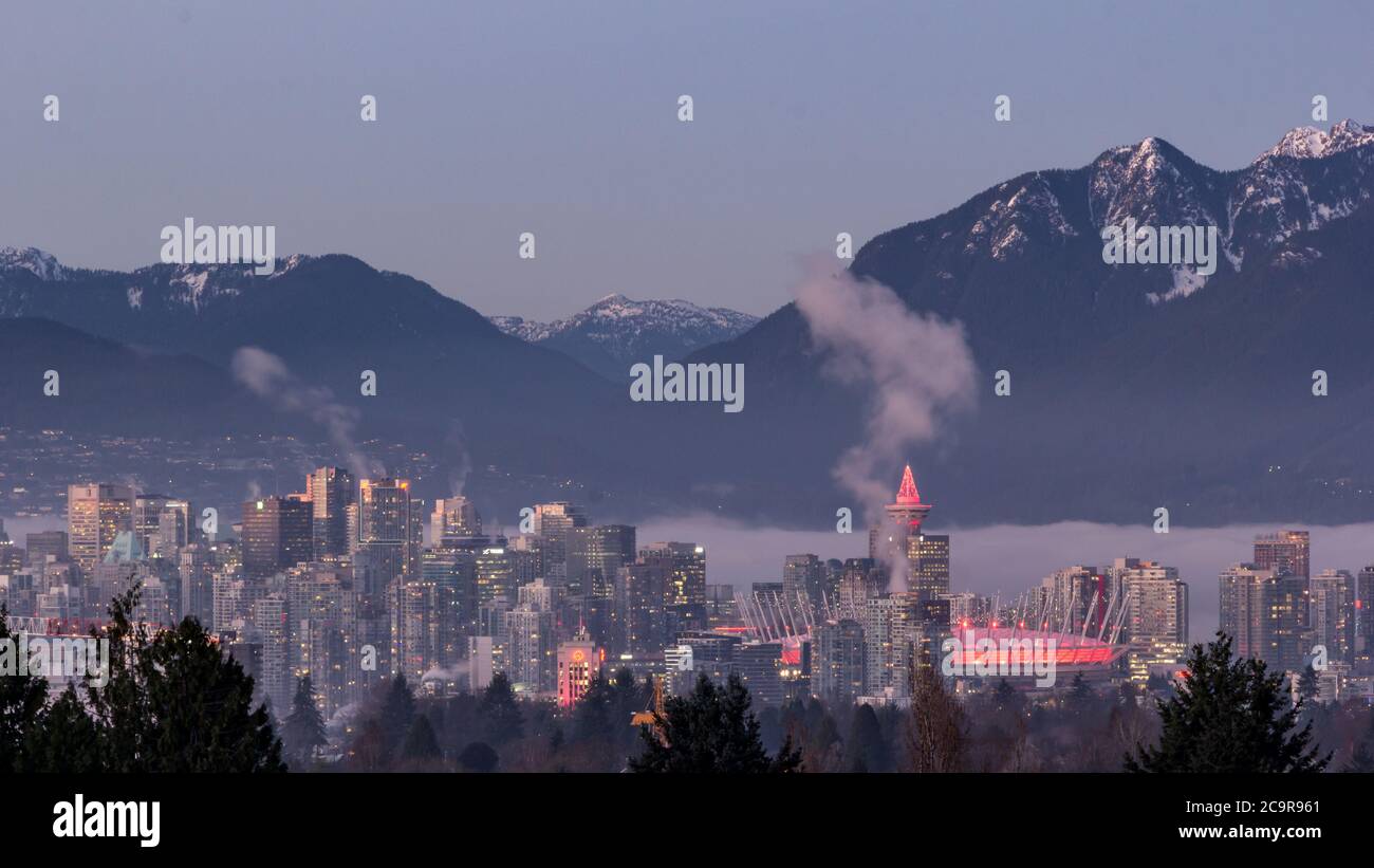 Skyline di Vancouver di notte - Vista aerea dal Queens Elizabeth Park in inverno con montagne innevate sullo sfondo Foto Stock