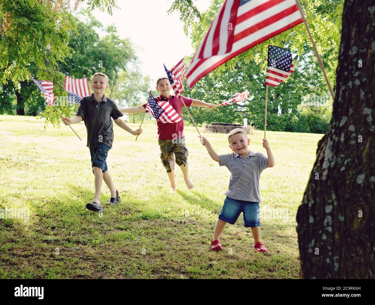 Tre ragazzi che tengono le bandiere americane entusiasticamente mentre le agitavano Foto Stock