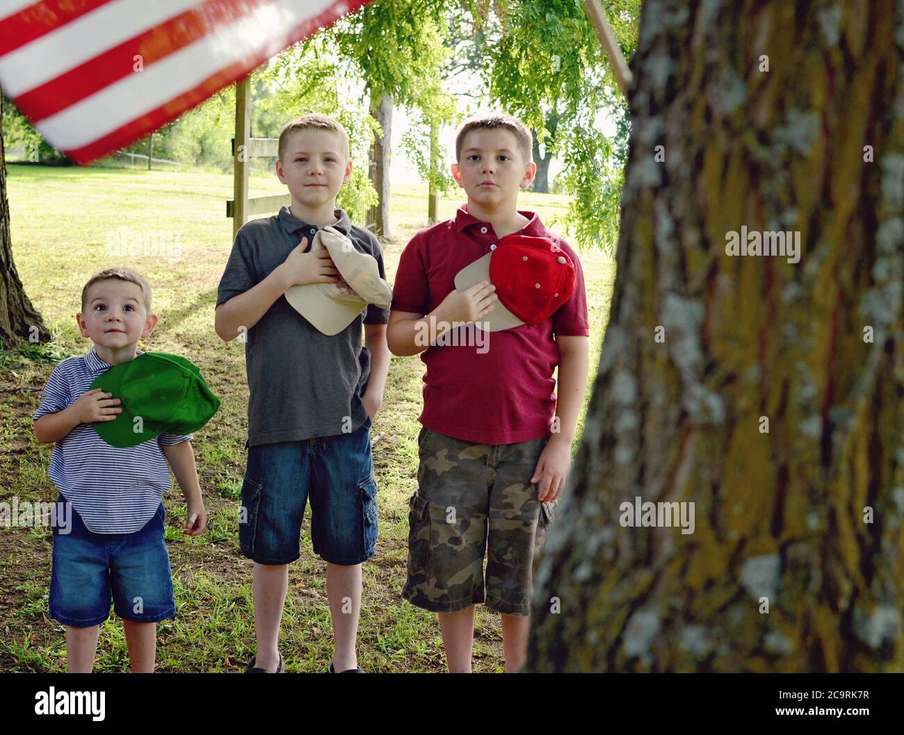 Tre ragazzi che si sono Uniti alla bandiera americana Foto Stock