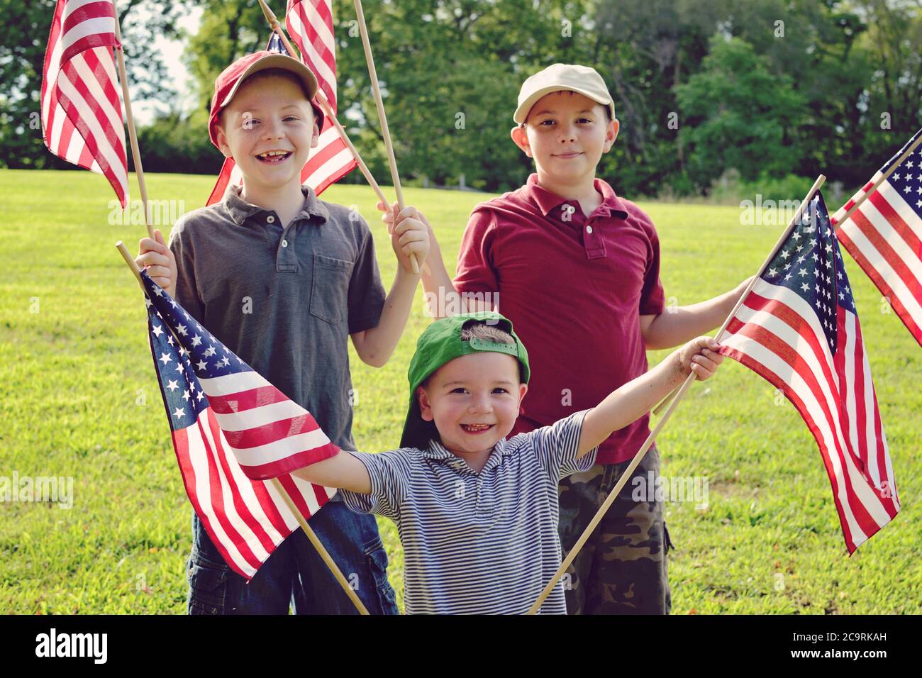 Tre ragazzi che tengono le bandiere americane entusiasticamente mentre le agitavano Foto Stock