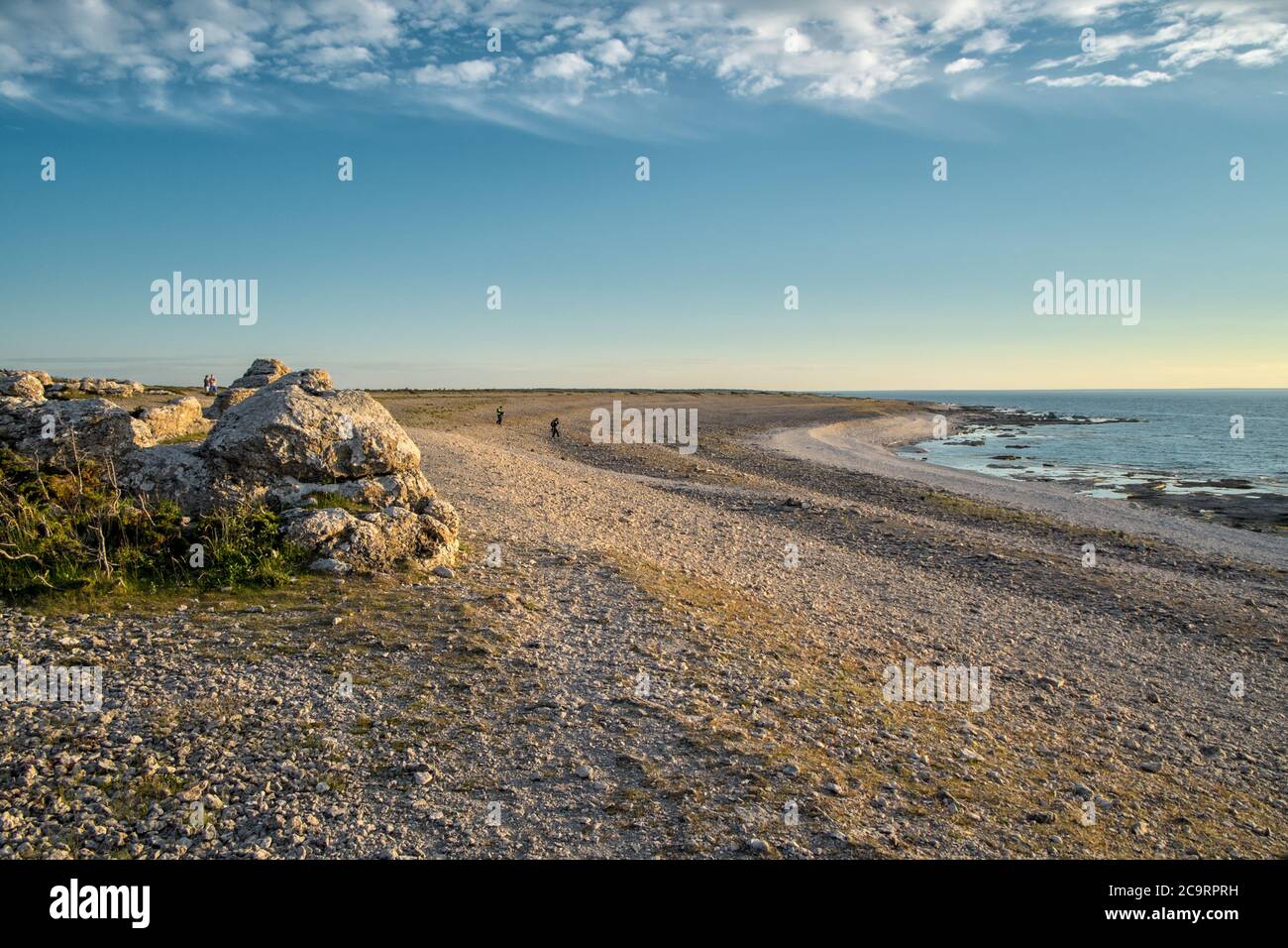 I turisti in lontananza godono del tramonto a Langhammar sull'isola svedese del Mar Baltico Faro fuori Gotland Foto Stock
