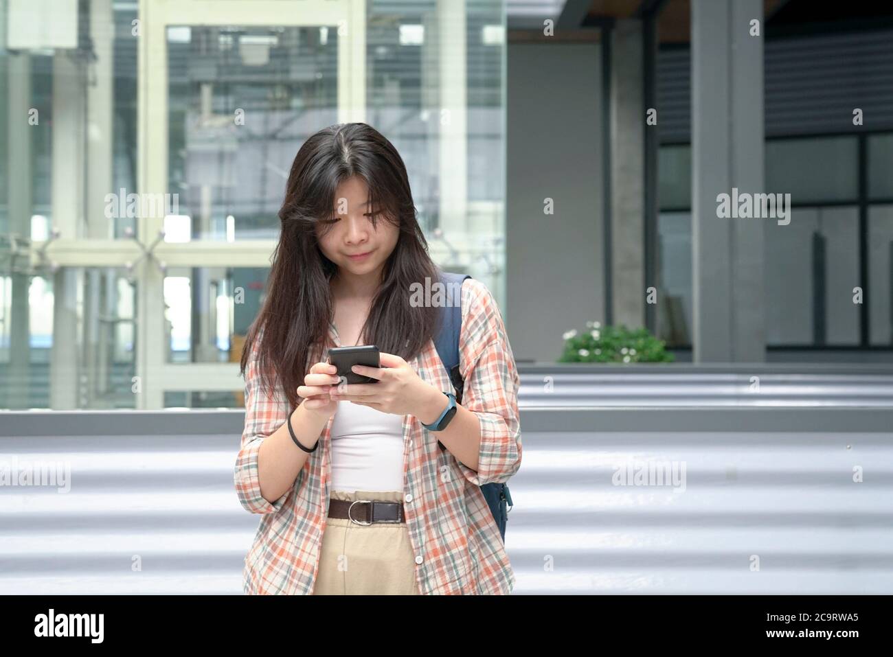 Giovane ragazza cinese che usa il suo cellulare per inviare SMS o messaggi. Concetto di stile di vita digitale. Foto Stock