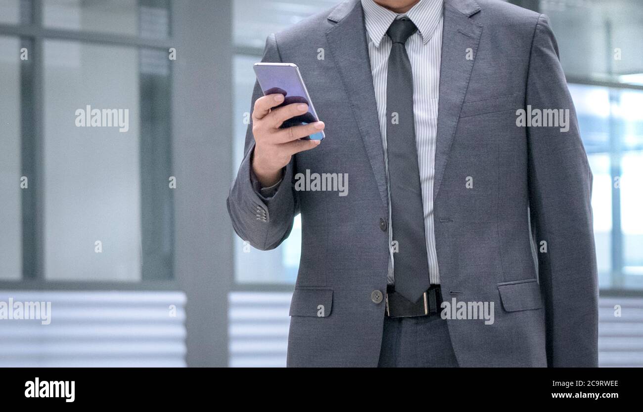 Uomo d'affari in cravatta e vestito che tiene un cellulare in mano. Spazio di copia. Foto Stock