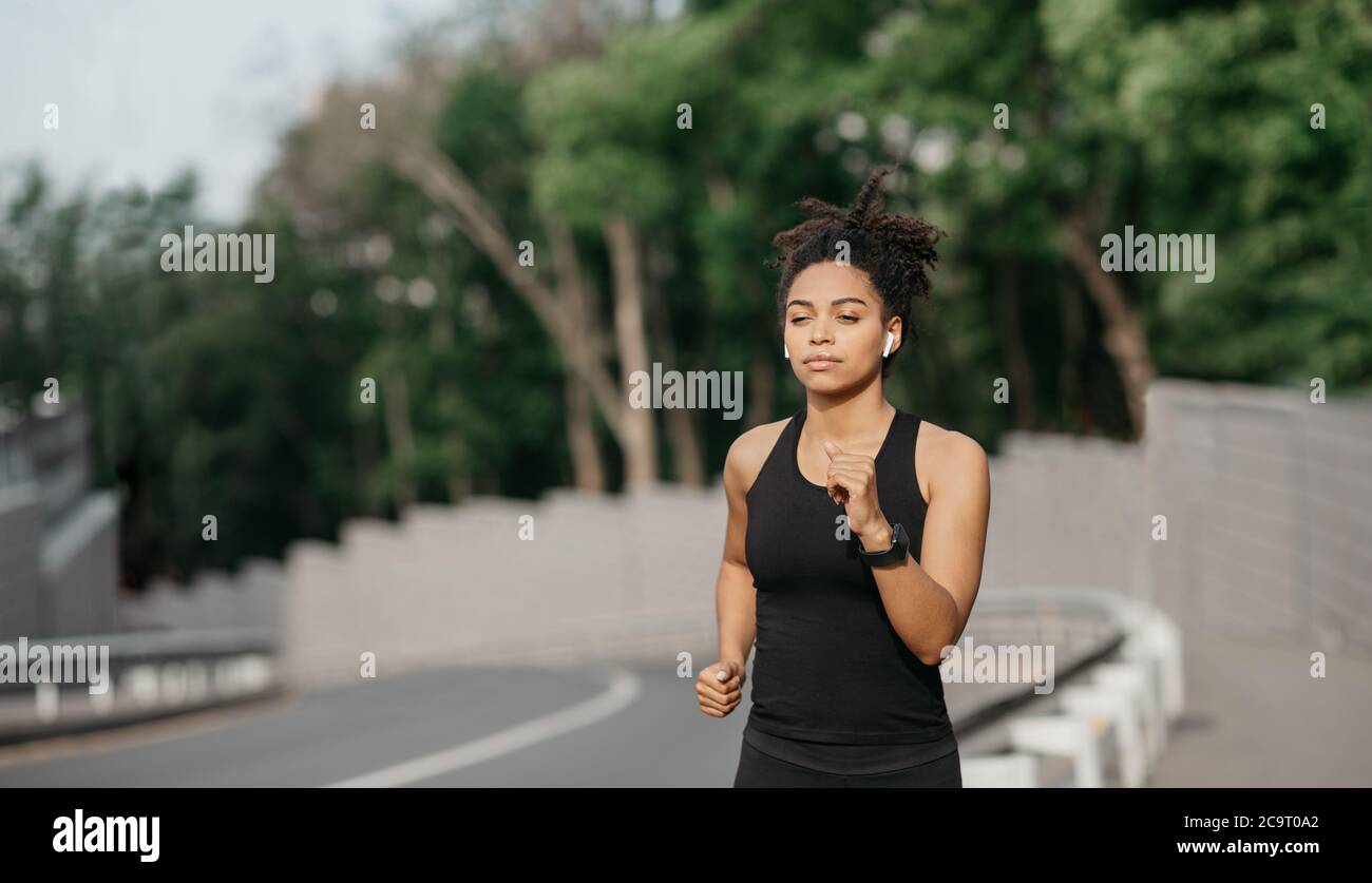 Donna sana e in forma. Concentrata afroamericana ragazza che corre su passerella Foto Stock