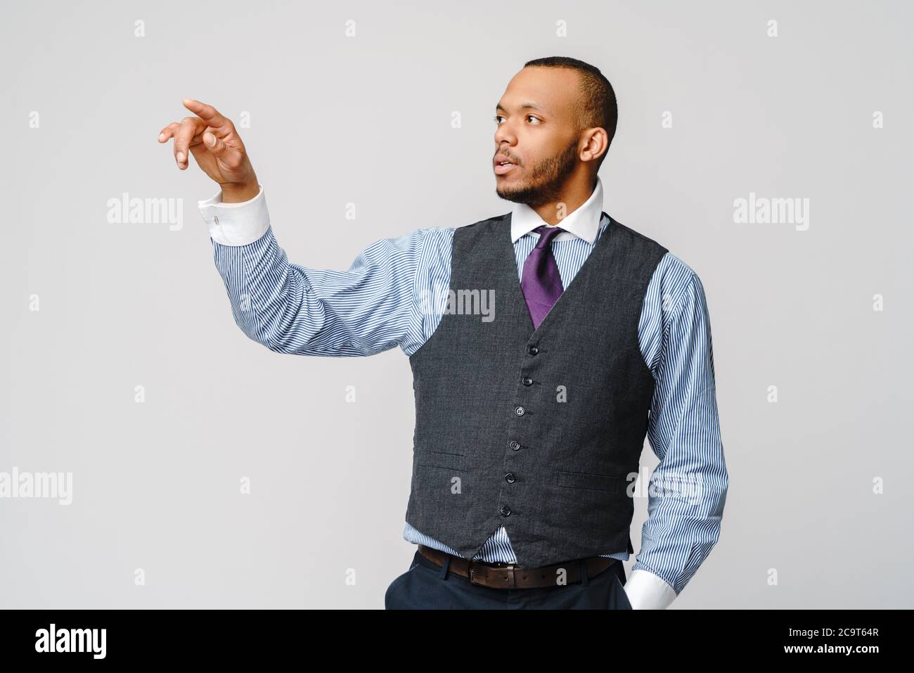 Bel giovane uomo d'affari afro-americano che punta il dito verso l'immagine o il testo dello schermo virtuale Foto Stock