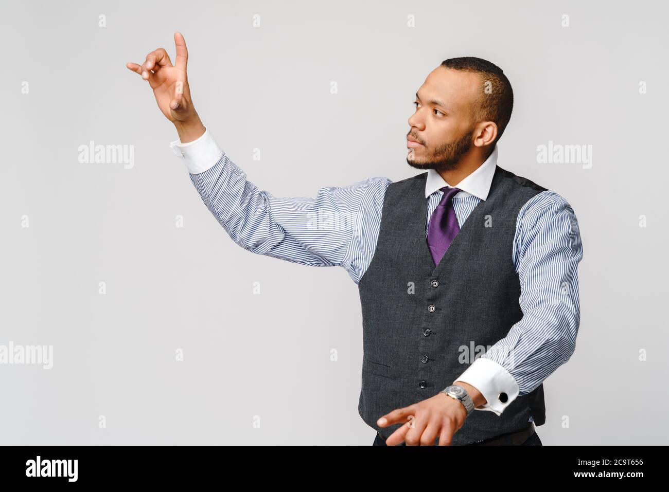 Bel giovane uomo d'affari afro-americano che punta il dito verso l'immagine o il testo dello schermo virtuale Foto Stock