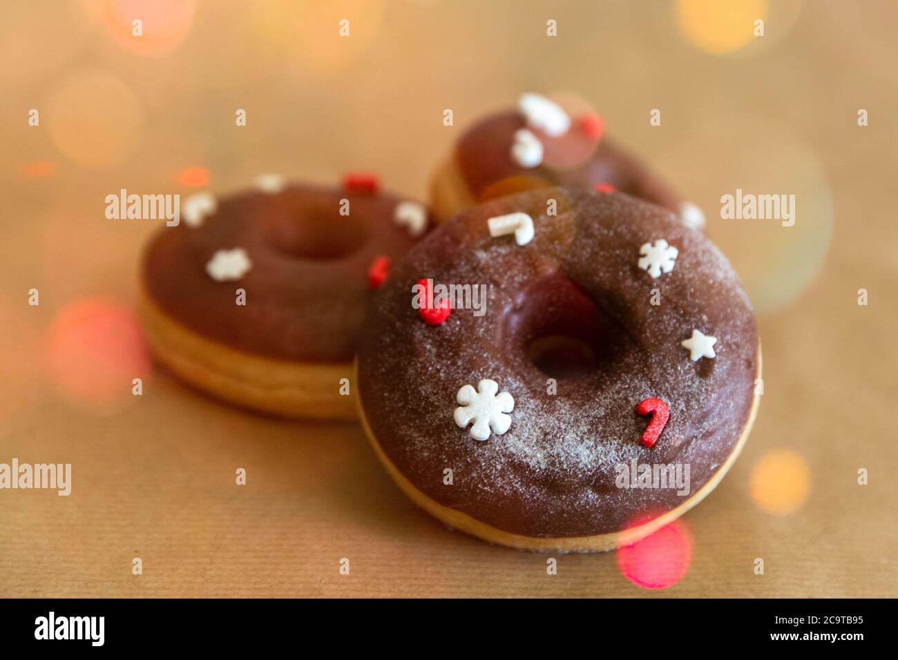 Ciambelle di cioccolato di Natale decorate rosso e bianco spruzzi con luci blured, fuoco selettivo Foto Stock
