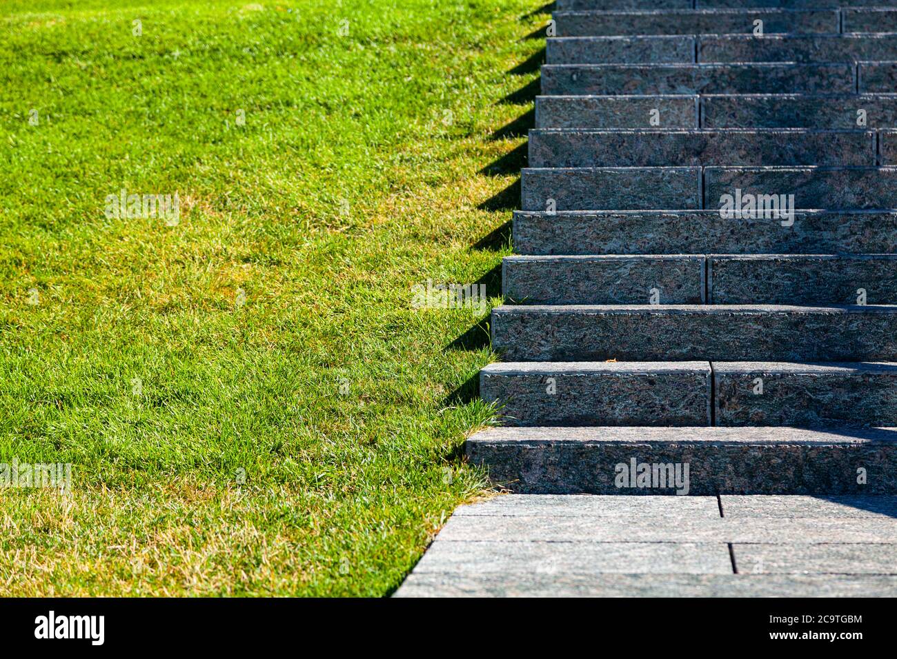 Scale in pietra e prato, primo piano. Gradini grigi e erba nel parco, frammento. Foto Stock