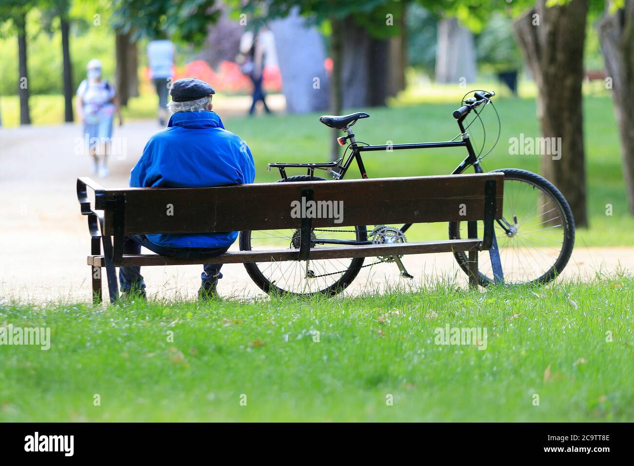 Madrid, Spagna - 31 maggio 2020: Anziano seduto su una panchina accanto alla sua bicicletta nel parco del Retiro a Madrid, Spagna. Foto Stock