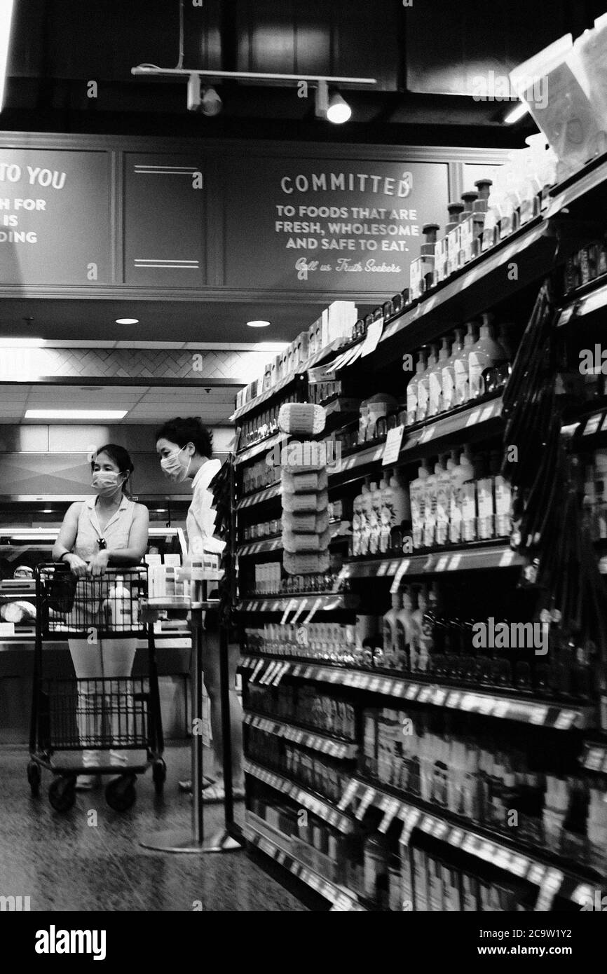 Foto in bianco e nero di due maschere che indossano acquirenti e cart nel negozio Whole Foods locale, Phase 3, Ottawa, Ontario, Canada. Foto Stock