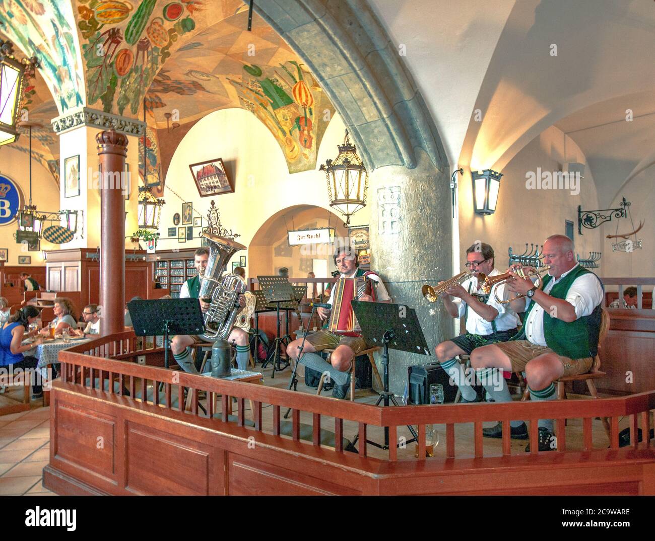 In costume da liederhosen bavarese tradizionale, la band oompah dell'Hofbrauhaus di Monaco intrattiene i commensali con la tipica musica bavarese. Foto Stock