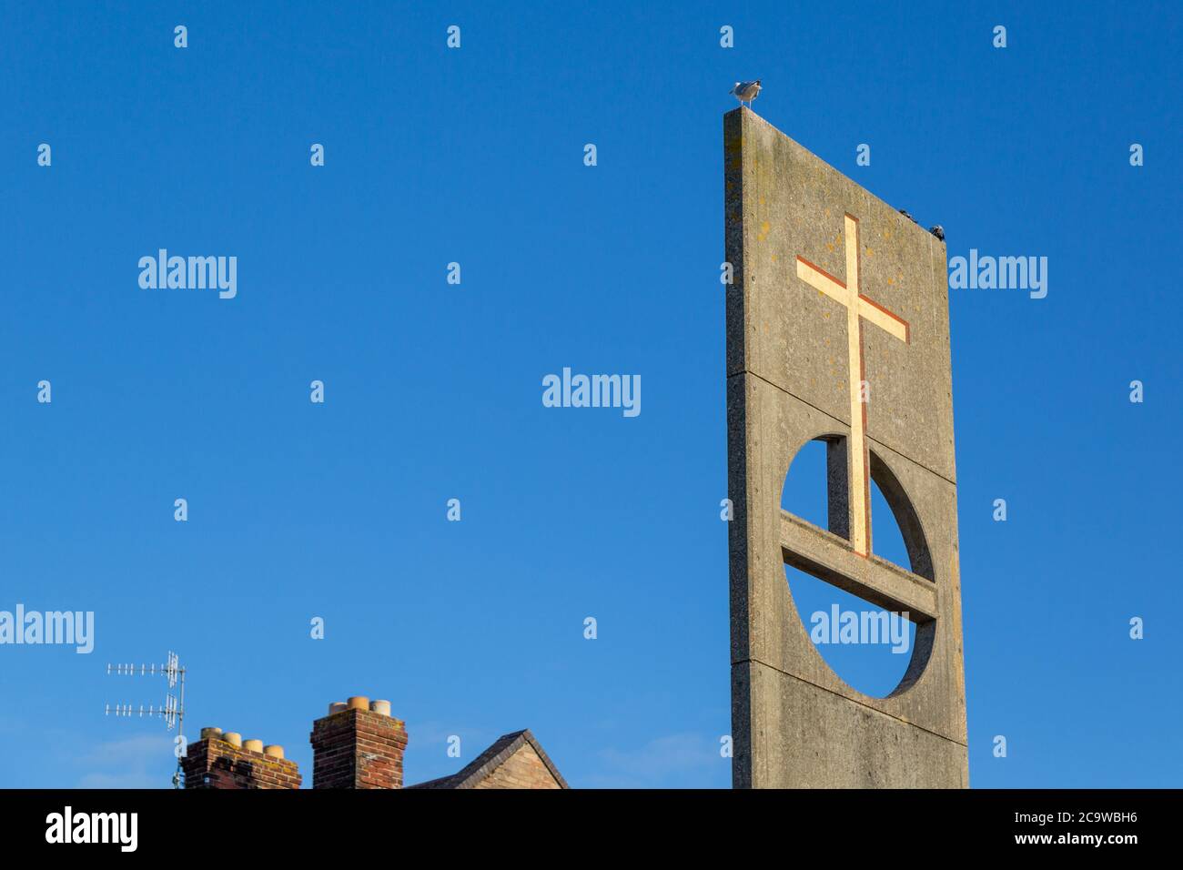una croce su una base fuori una chiesa Foto Stock