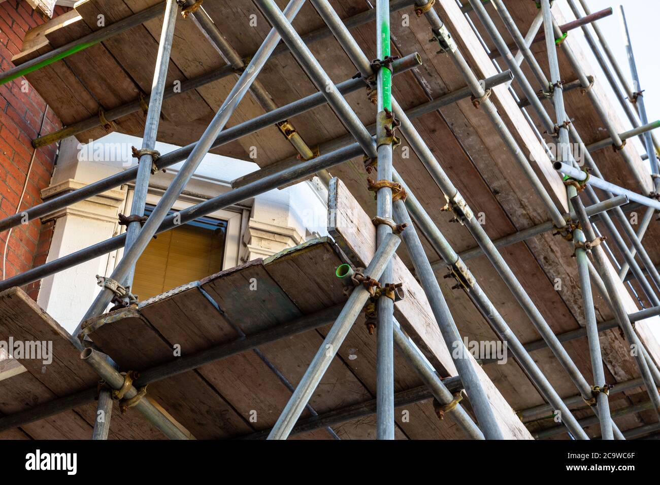 un primo piano di pali di impalcatura che circondano una casa sotto ristrutturazione Foto Stock